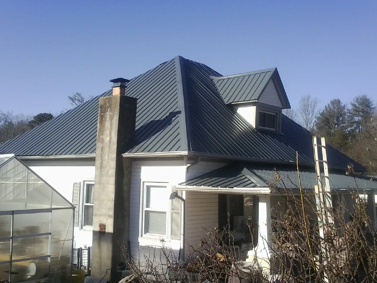 Dark blue standing seam metal roof on a white farmhouse with dormer — Slate & Tile Roof Repair by Roofing Brothers in Ridgeway