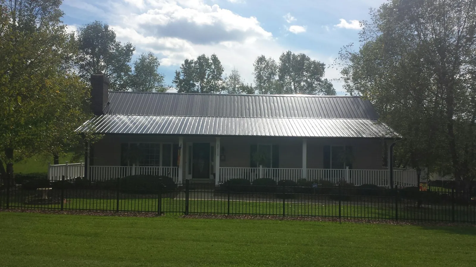 Gray metal roof on a brick ranch with a full width front porch — Gutter Guard Installation work by our crew in Ridgeway